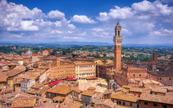 Luftaufnahme einer italienischen Stadt mit zentralem Turm und historischen Gebäuden.