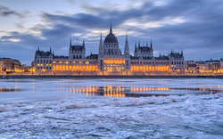 Parlamentsgebäude in Budapest bei Abenddämmerung mit gefrorenem Fluss.