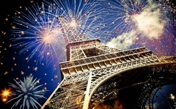 Eiffelturm mit buntem Feuerwerk im Hintergrund bei Nacht.