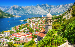 Mittelalterlicher Glockenturm mit Blick auf Küstenstadt Kotor, umgeben von Bergen und Meer.